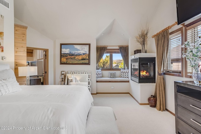 bedroom featuring a multi sided fireplace, light carpet, vaulted ceiling, and multiple windows