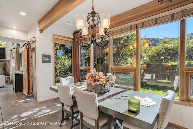 dining room featuring a mountain view, beam ceiling, a barn door, light tile patterned floors, and a chandelier