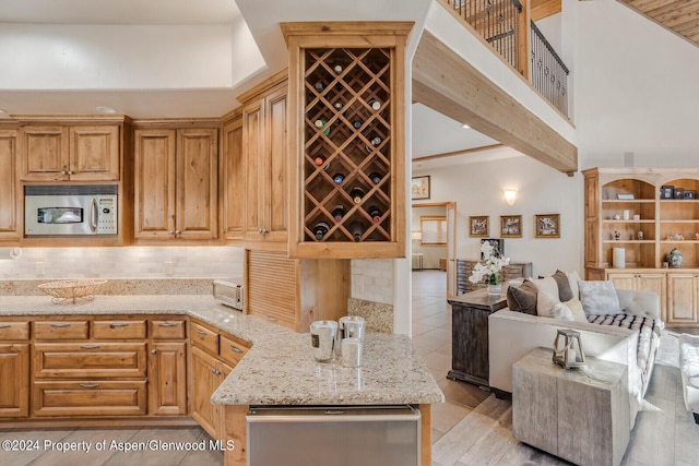 kitchen featuring light stone countertops, a high ceiling, and backsplash