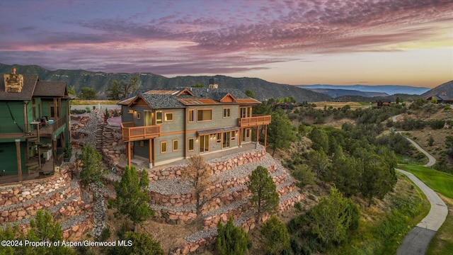 back house at dusk featuring a mountain view and a balcony