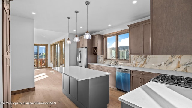 kitchen with decorative light fixtures, a center island, sink, and appliances with stainless steel finishes