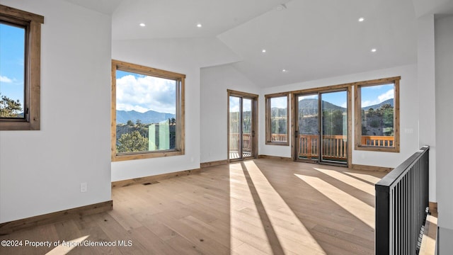 empty room with a mountain view, light hardwood / wood-style floors, and vaulted ceiling