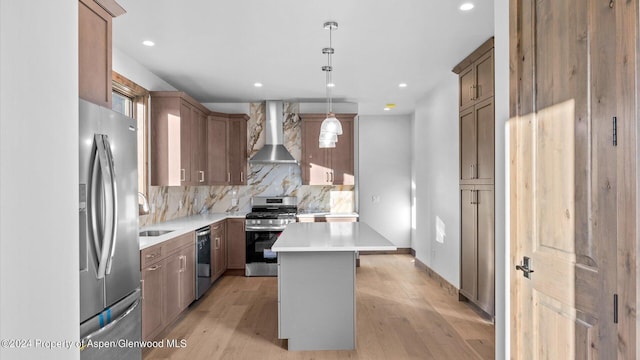 kitchen featuring pendant lighting, wall chimney exhaust hood, decorative backsplash, a kitchen island, and stainless steel appliances