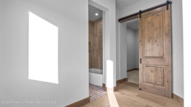 corridor featuring a barn door and light hardwood / wood-style flooring