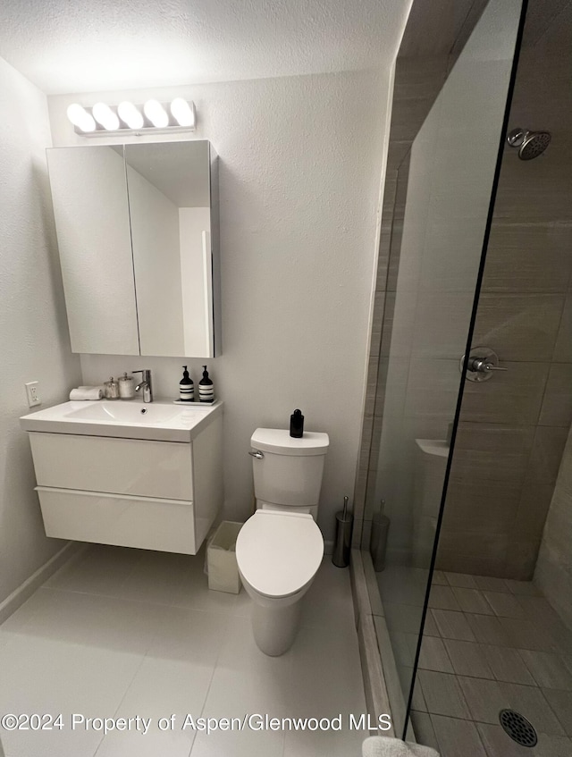 bathroom featuring a tile shower, vanity, toilet, tile patterned floors, and a textured ceiling