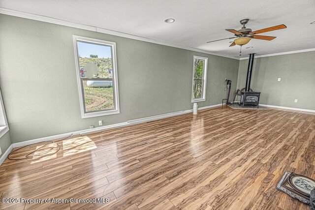 5990 County Road 7, Craig, CO 81625 - unfurnished living room with ornamental molding, a wood stove, wood finished floors, baseboards, and a ceiling fan