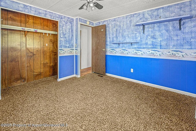 5990 County Road 7, Craig, CO 81625 - unfurnished bedroom with wallpapered walls, carpet flooring, ceiling fan, and a closet
