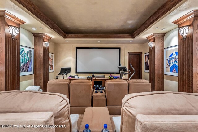 cinema room featuring a raised ceiling and decorative columns