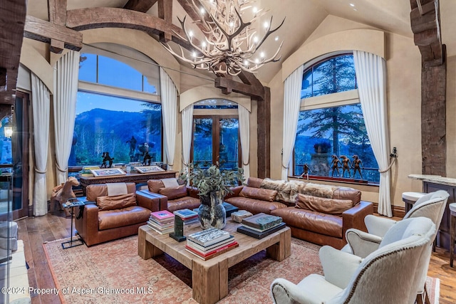 living room featuring french doors, wood-type flooring, high vaulted ceiling, a mountain view, and a chandelier