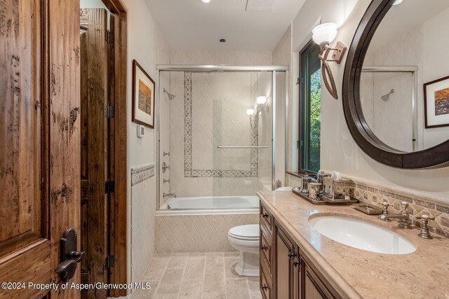 full bathroom with tile patterned flooring, toilet, vanity, and combined bath / shower with glass door