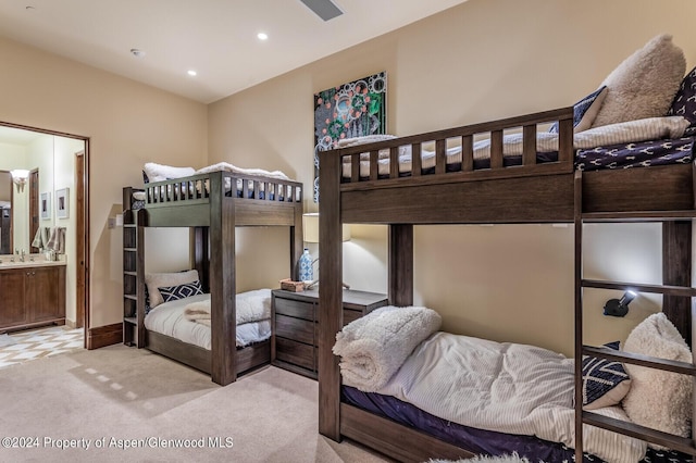 bedroom featuring connected bathroom, sink, and light colored carpet