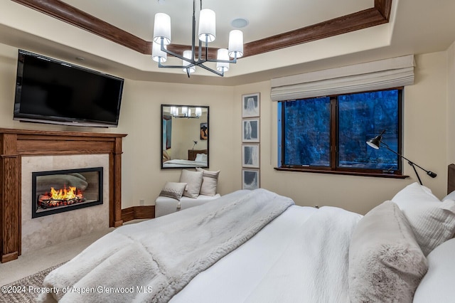 carpeted bedroom featuring ornamental molding, a fireplace, a tray ceiling, and a chandelier