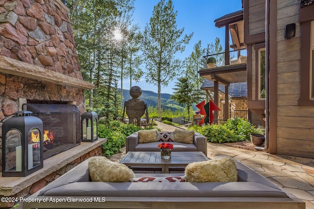 view of patio with an outdoor living space with a fireplace, a mountain view, and a balcony