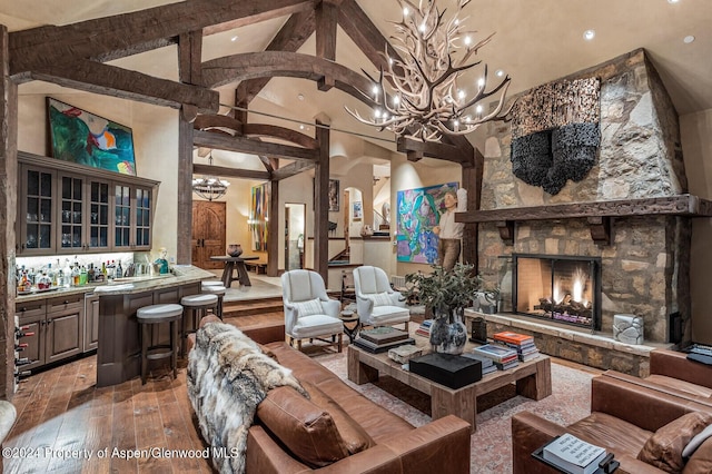 living room featuring beam ceiling, hardwood / wood-style flooring, high vaulted ceiling, a stone fireplace, and bar