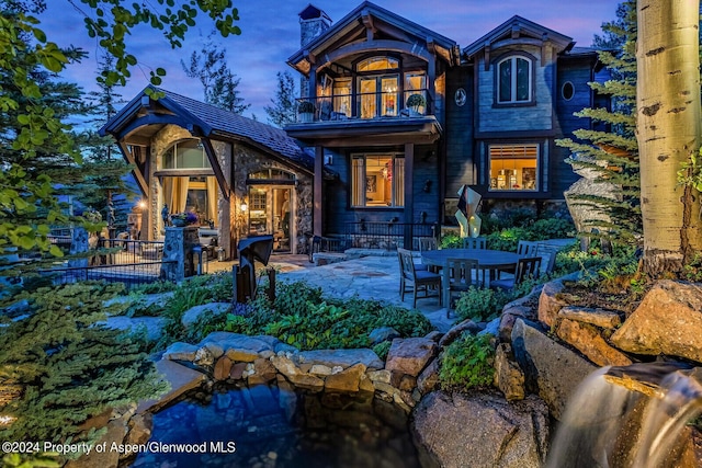 back house at dusk with a patio area and a balcony