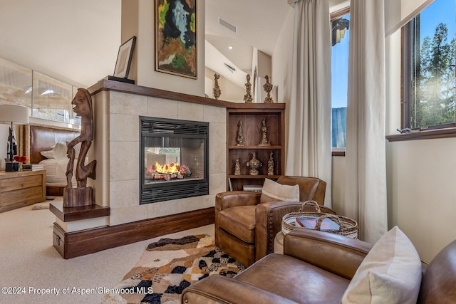 living area featuring carpet flooring, a tile fireplace, and vaulted ceiling