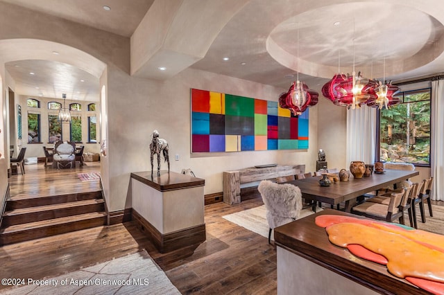 dining area featuring a chandelier, a tray ceiling, and dark wood-type flooring