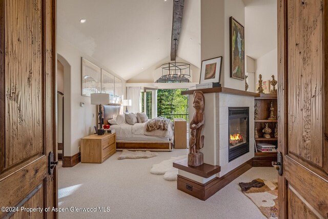 living area featuring vaulted ceiling with beams, light colored carpet, and a tile fireplace