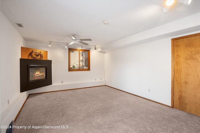 unfurnished living room with carpet flooring, track lighting, and ceiling fan