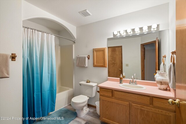 full bathroom with hardwood / wood-style floors, vanity, shower / tub combo, and toilet