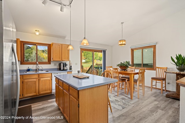 kitchen with sink, stainless steel fridge, decorative light fixtures, dishwashing machine, and a kitchen island