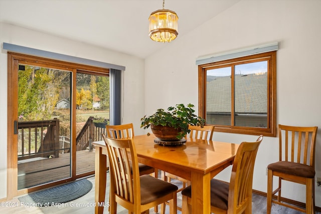 dining area featuring hardwood / wood-style floors, lofted ceiling, a wealth of natural light, and an inviting chandelier