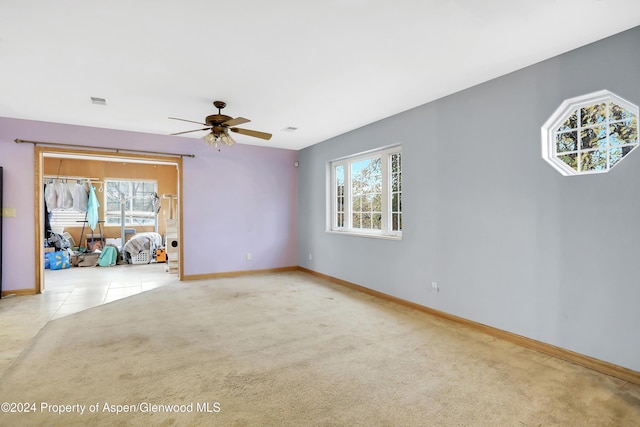 empty room featuring plenty of natural light, ceiling fan, and light colored carpet