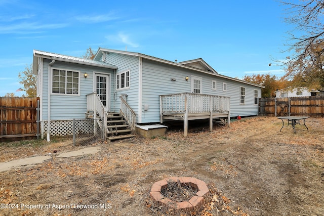 rear view of house with a fire pit and a wooden deck