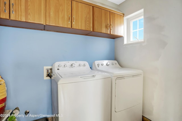 clothes washing area with cabinets and washer and clothes dryer