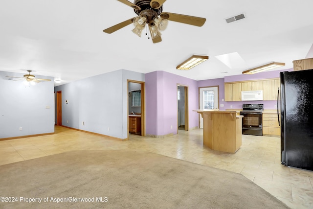 kitchen with a skylight, ceiling fan, black appliances, a center island, and light tile patterned flooring