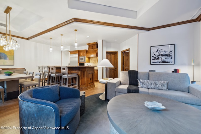 living room with a tray ceiling and light hardwood / wood-style floors