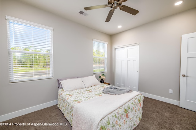 bedroom with multiple windows, a closet, dark carpet, and ceiling fan