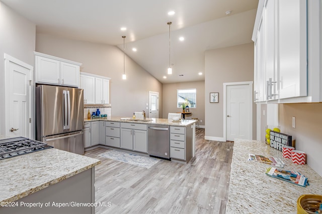 kitchen with light stone countertops, hanging light fixtures, white cabinets, and stainless steel appliances