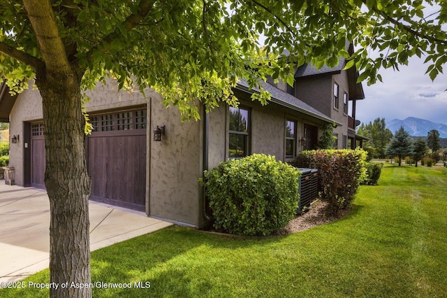 289 Sweetgrass Dr, Carbondale, CO 81623 - view of side of property with an attached garage, a mountain view, a shingled roof, a lawn, and stucco siding