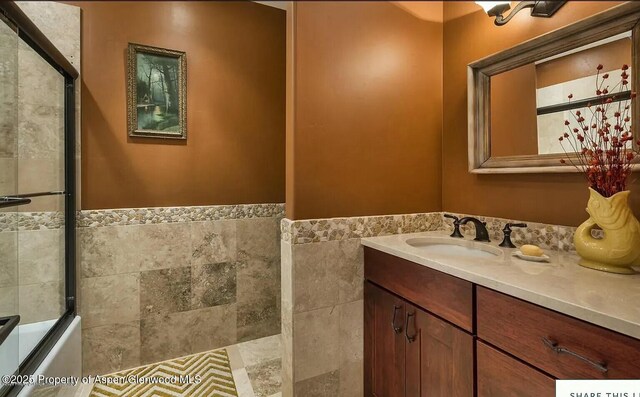 289 Sweetgrass Dr, Carbondale, CO 81623 - bathroom with wainscoting, a shower with shower door, tile walls, and vanity