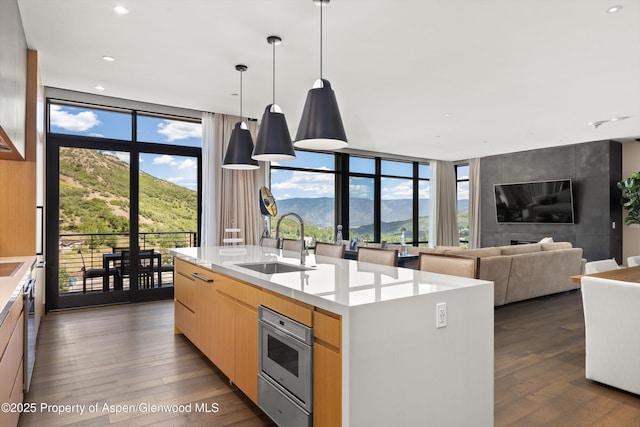 45 Wood Rd Unit 403, Snowmass Village, CO 81615 - kitchen featuring dark wood-style flooring, a center island with sink, a wall of windows, light brown cabinetry, and light countertops