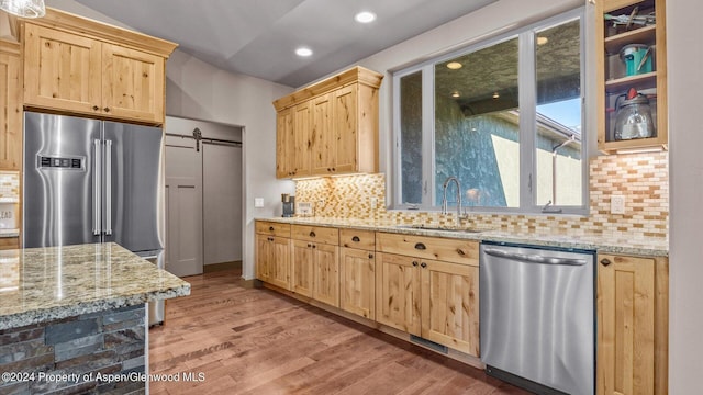 kitchen featuring appliances with stainless steel finishes, a barn door, light brown cabinets, and sink