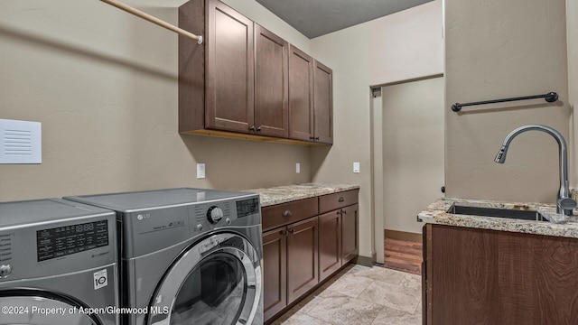 clothes washing area with washer and clothes dryer, cabinets, and sink