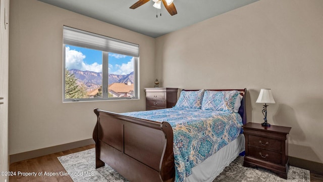 bedroom with a mountain view, ceiling fan, and light hardwood / wood-style floors