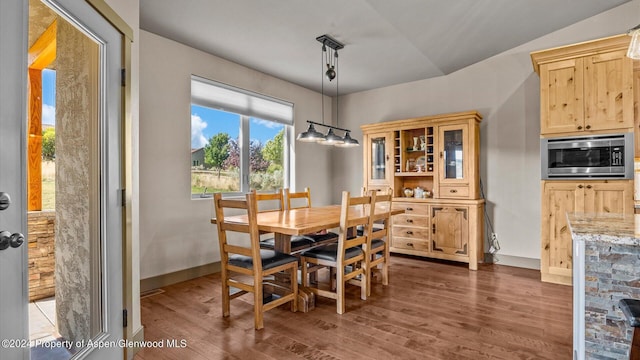 dining area with dark wood-type flooring and vaulted ceiling