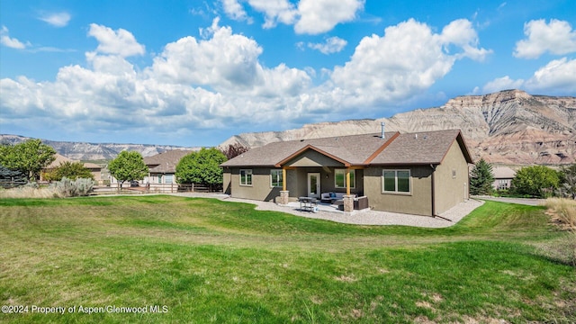 back of house featuring a mountain view, outdoor lounge area, a yard, and a patio area