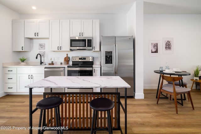 766 Tucker St, Craig, CO 81625 - kitchen featuring a kitchen breakfast bar, stainless steel appliances, baseboards, a sink, and light wood-style flooring