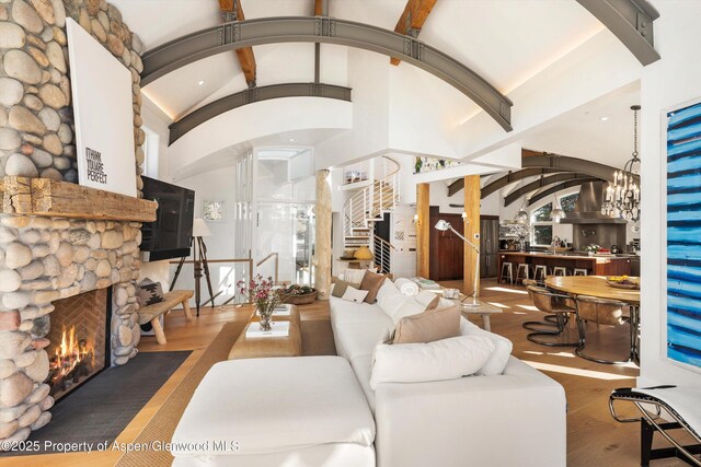 63 Smuggler Grove Rd, Aspen, CO 81611 - living room with arched walkways, a stone fireplace, stairs, wood finished floors, and beam ceiling