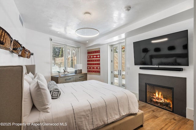 63 Smuggler Grove Rd, Aspen, CO 81611 - bedroom featuring a warm lit fireplace, wood finished floors, and access to outside
