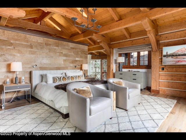 bedroom with light wood-type flooring, wood ceiling, beam ceiling, an inviting chandelier, and wood walls