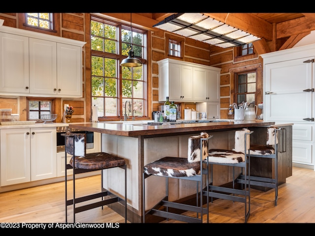 kitchen with wood walls, a kitchen bar, and white cabinetry