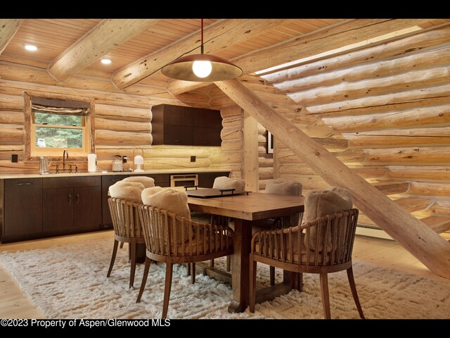 dining area with sink, log walls, beamed ceiling, light hardwood / wood-style floors, and wood ceiling