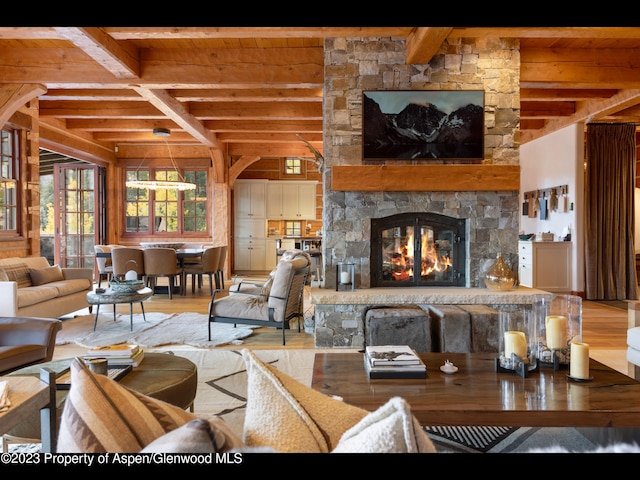 living room with wood-type flooring, a stone fireplace, and beam ceiling