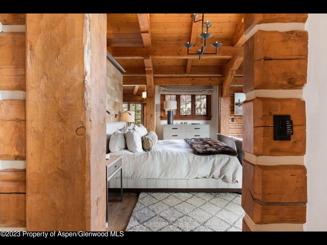 bedroom with beam ceiling, a chandelier, light hardwood / wood-style flooring, and wooden ceiling