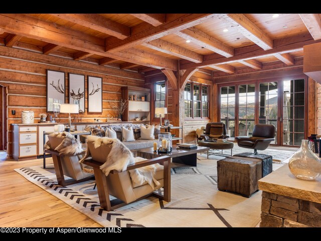 living room featuring beamed ceiling, wood walls, wood ceiling, and light hardwood / wood-style flooring